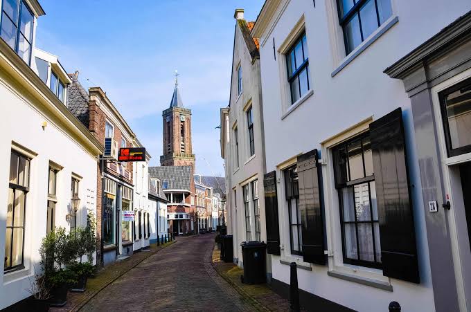 Straatje met witte gevels en luiken in Loenen aan de Vecht, met de kerktoren op de achtergrond